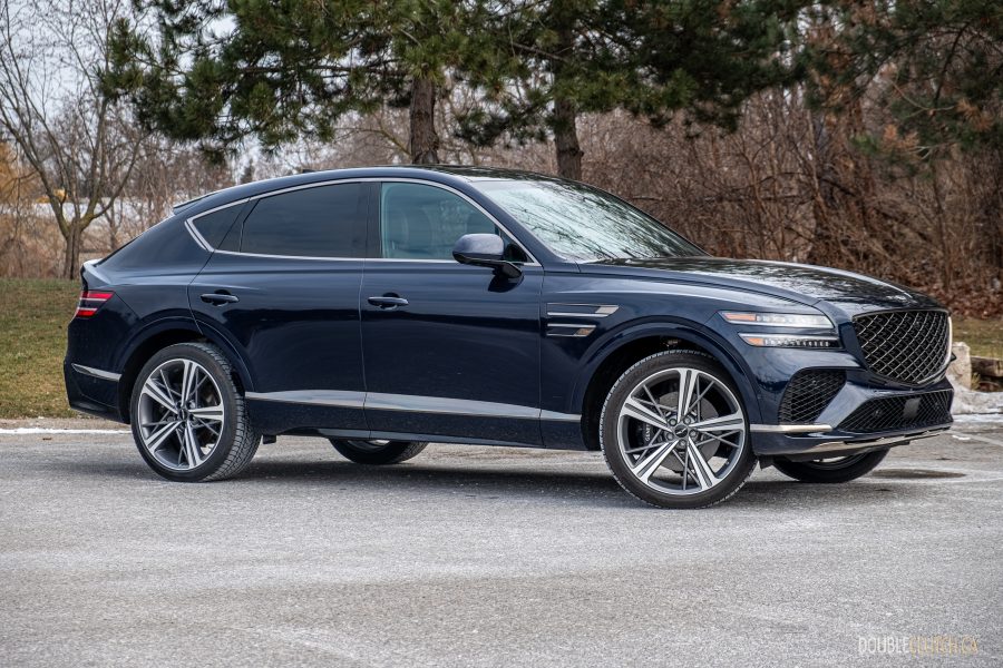 Front quarter view of a blue 2025 Genesis GV80 Coupe against a backdrop of trees